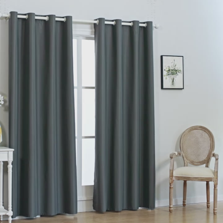 A pair of solid-colored blackout curtains featuring metal grommets at the top, hanging fully closed to block out natural light in a styled home interior.